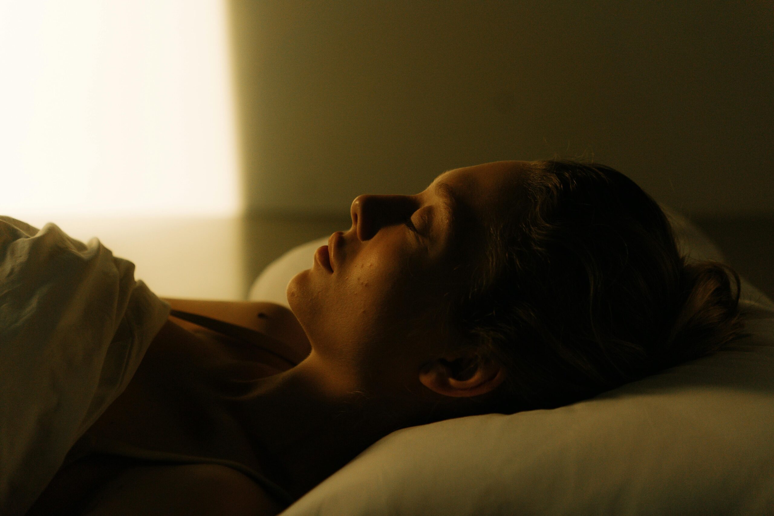 A calming scene of a woman lying in bed, peacefully asleep, bathed in warm light.